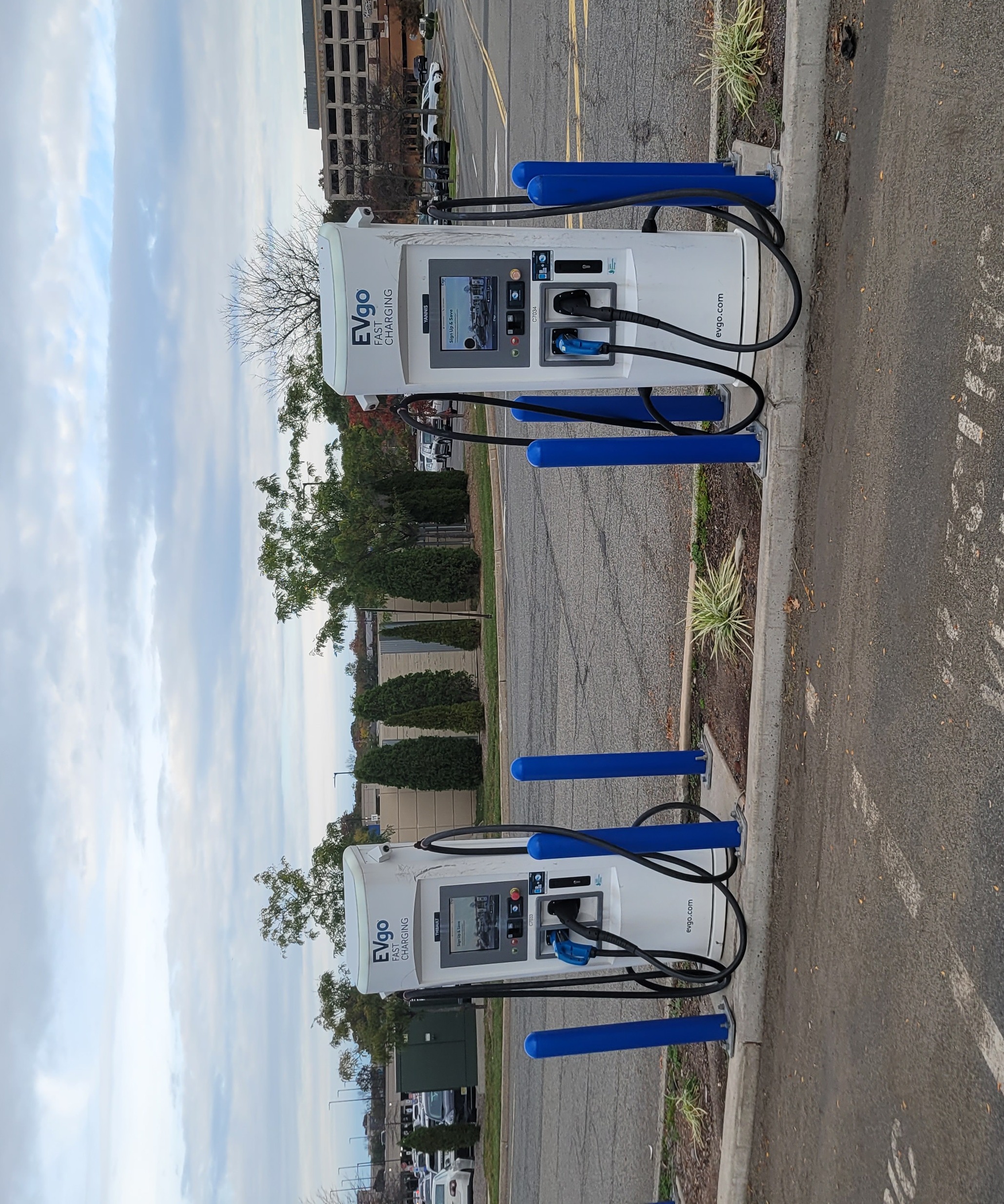Two EVgo charging dispensers in a shopping-center parking lot.