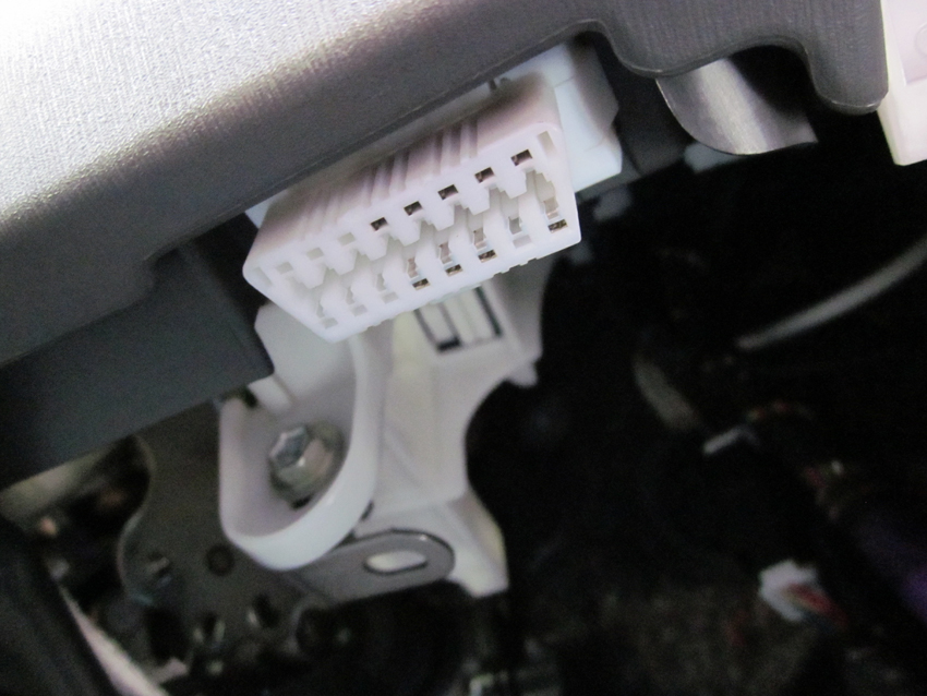 A vehicle diagnostic socket beneath the steering column.