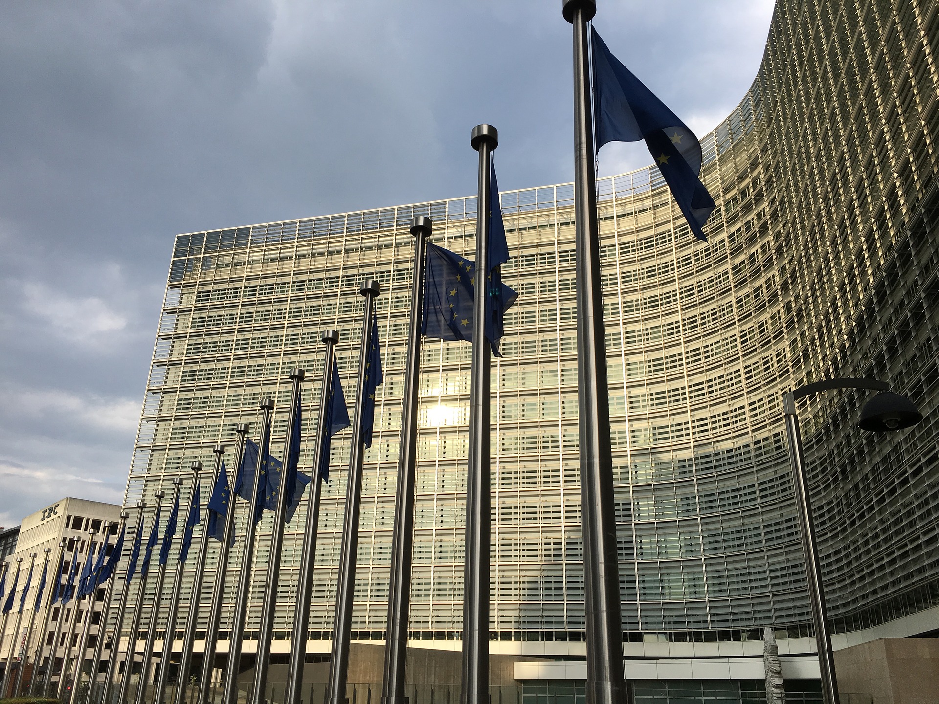 EU flags outside the curved glass façade of the Berlaymont building.