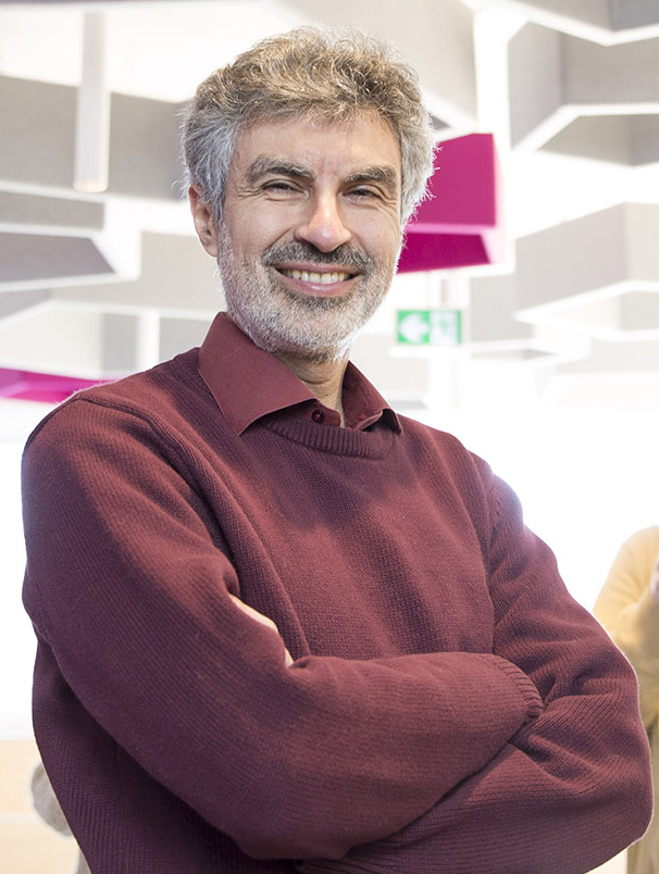 Yoshua Bengio stands with folded arms in a burgundy sweater.