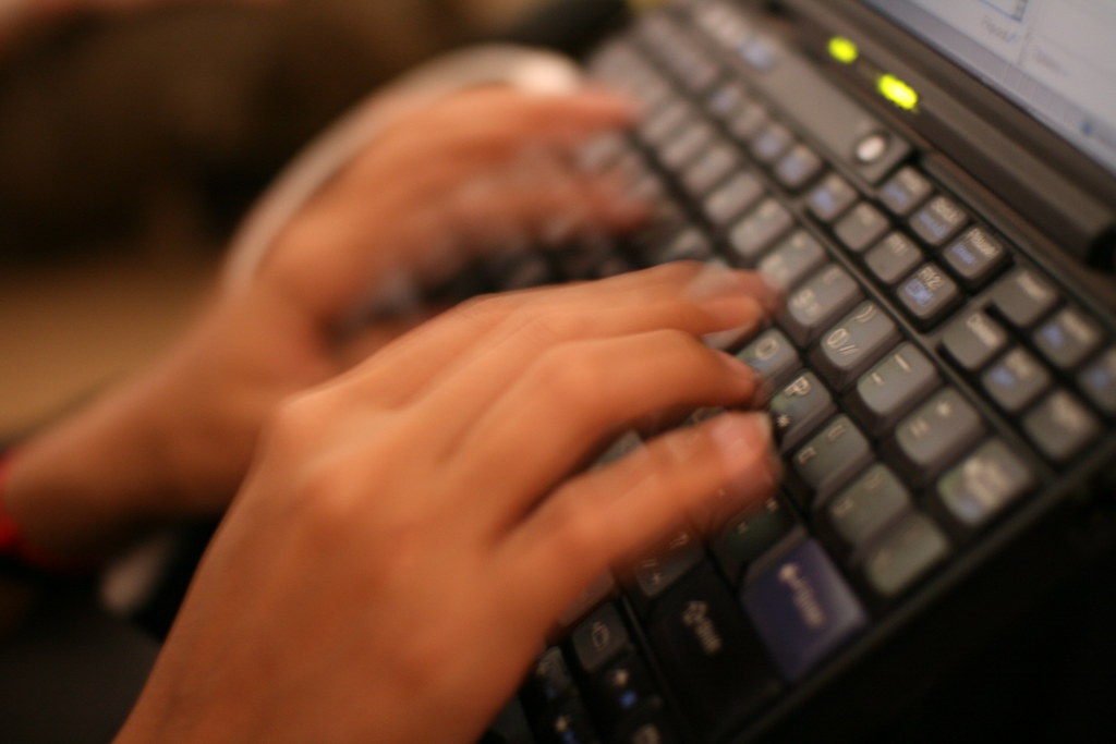 File photo: hands over a laptop keyboard, with motion blur.