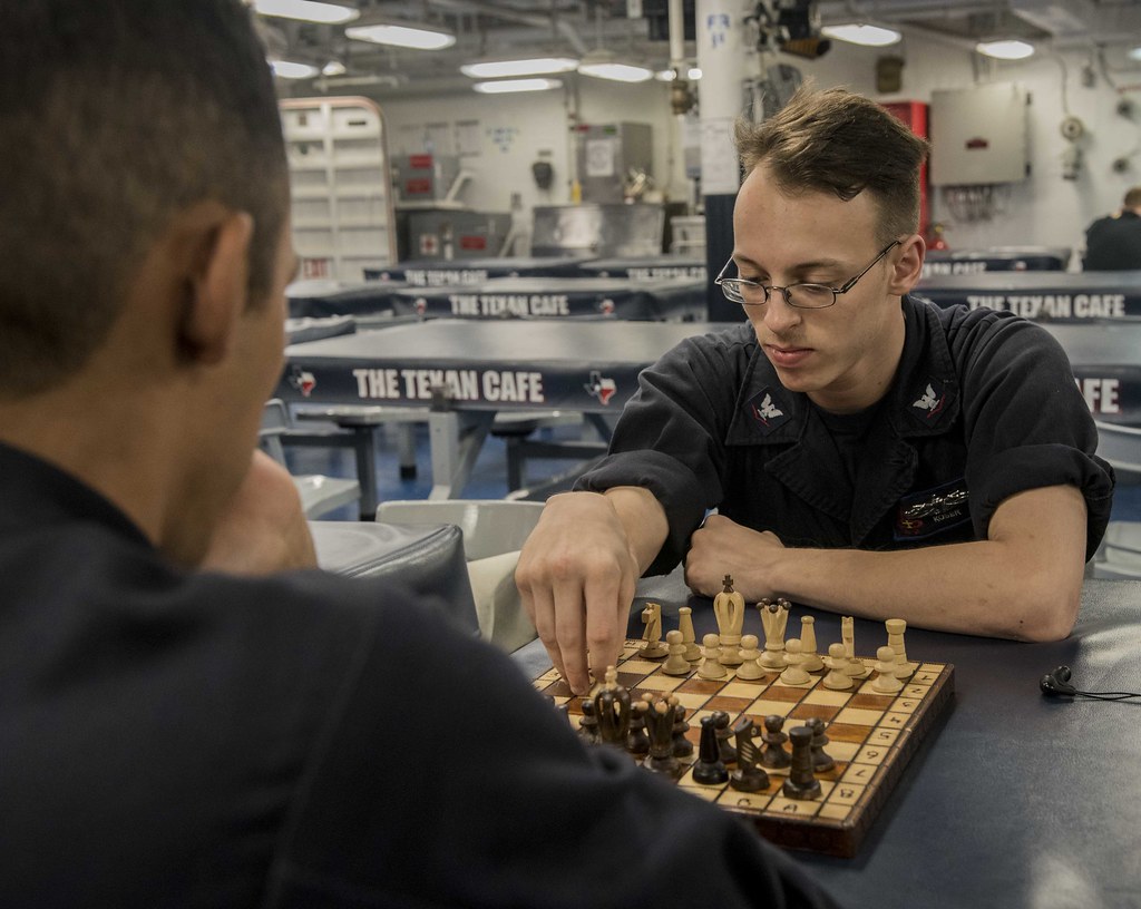 Two sailors play chess aboard a ship.