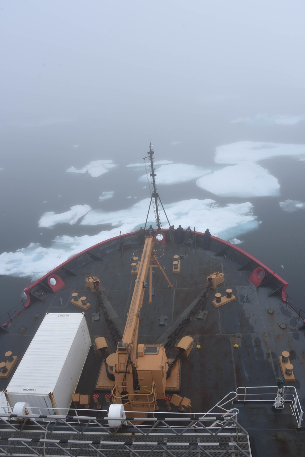 Ice floes and fog surround Healy’s bow and forward deck.