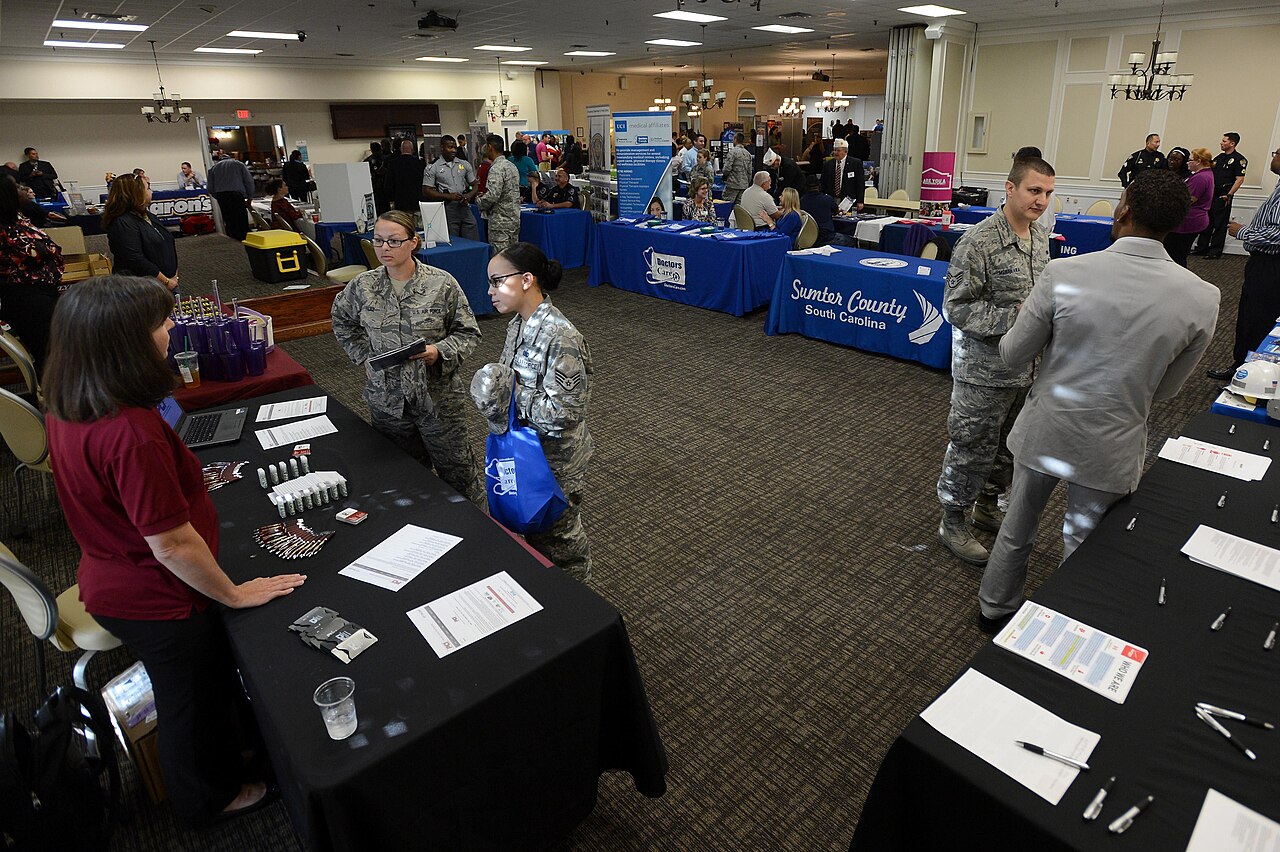 People speaking at employer and education tables in a hall.