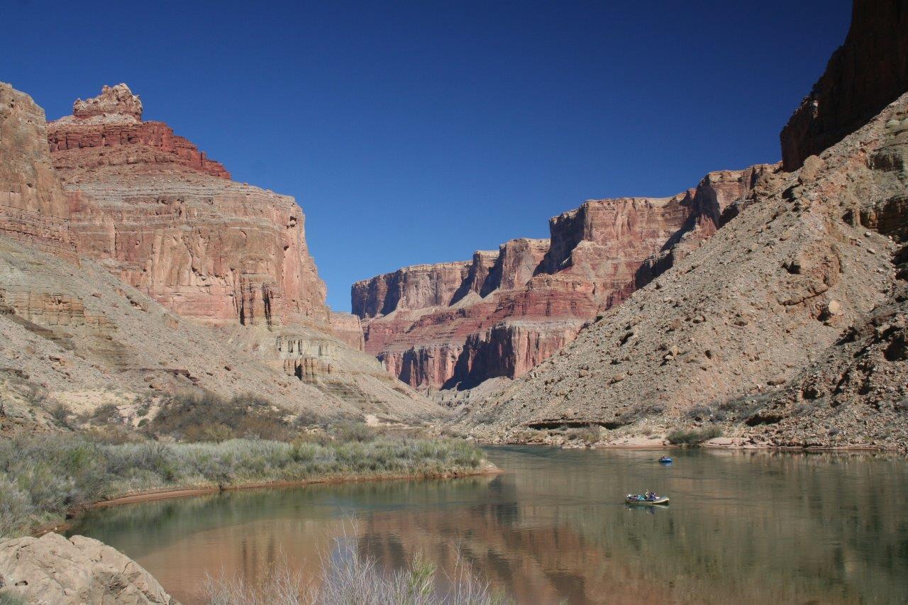 Boats on the Colorado River between the Grand Canyon’s rocky walls.
