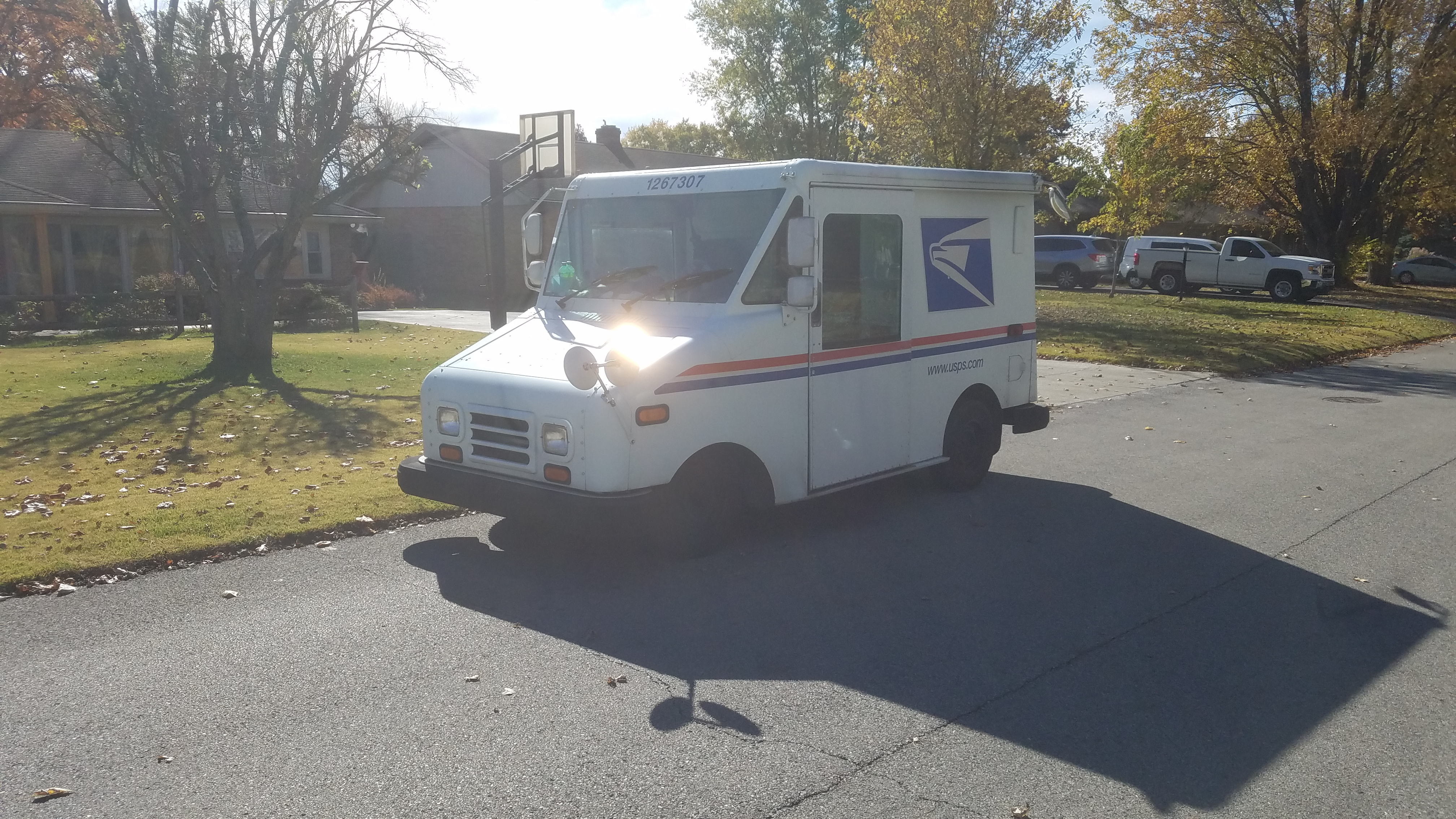 A postal delivery vehicle stands on a residential street.