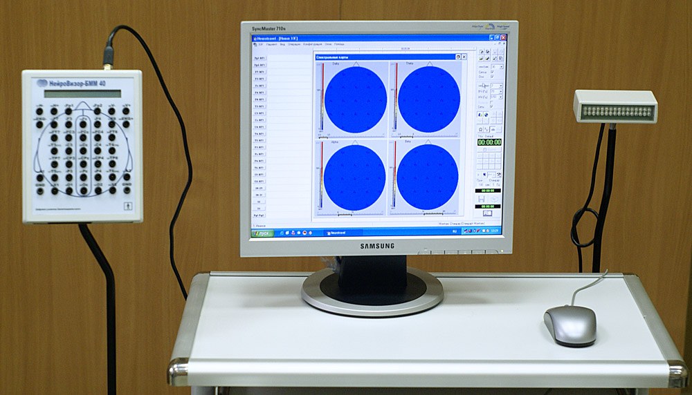 An EEG recorder, computer display and photic stimulator on a table.