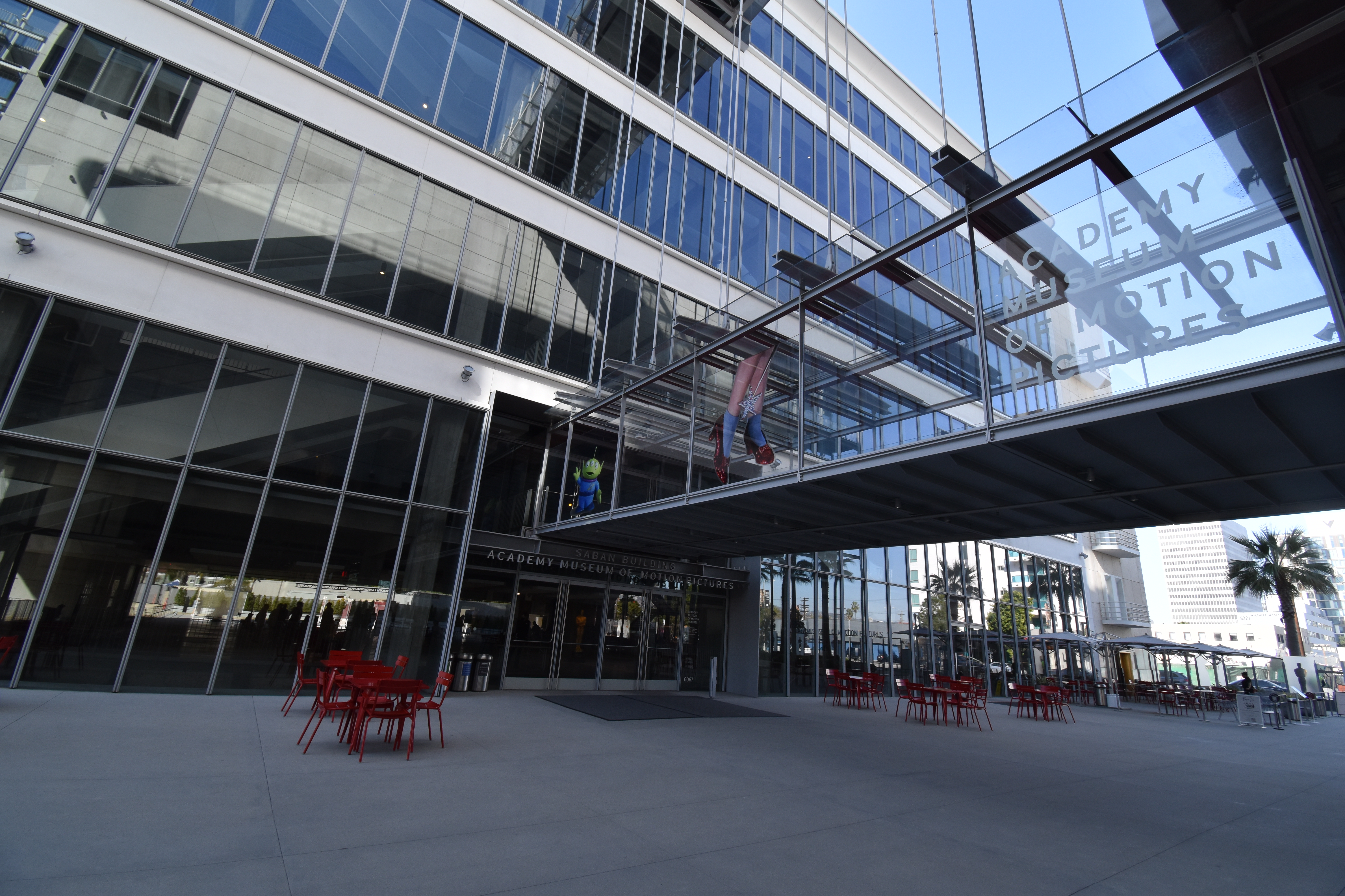 The Academy Museum entrance beneath a glass pedestrian bridge.