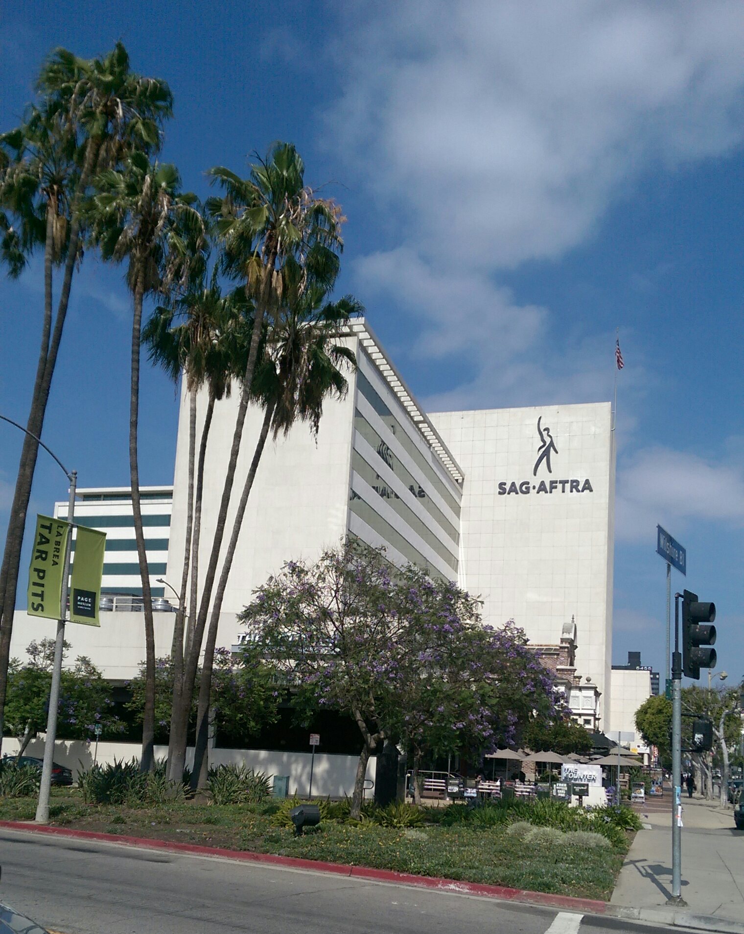 SAG-AFTRA signage on a tall building beside palm trees.