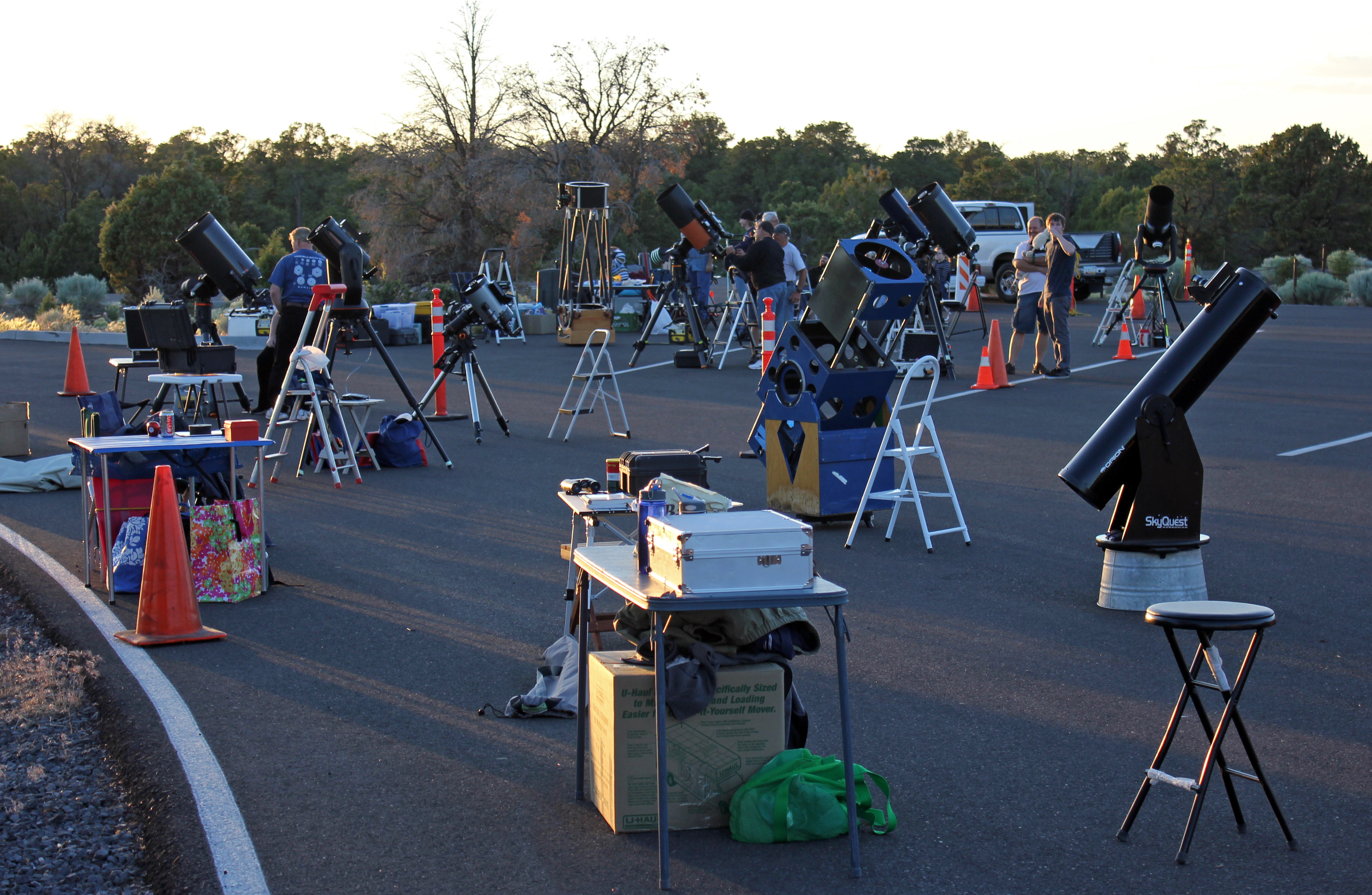 Telescopes and volunteers in a Grand Canyon parking lot before dark.