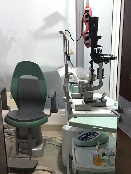 Empty examination chair beside eye-testing equipment.