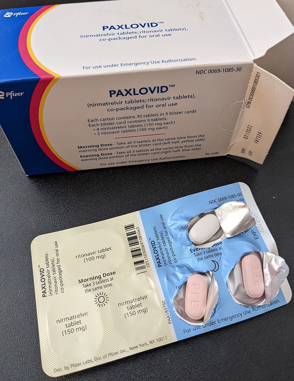 An opened blister reveals pink and white tablets.