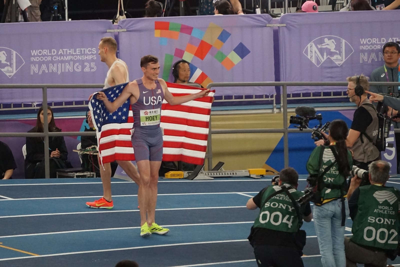 Josh Hoey holding a United States flag at the 2025 indoor championships.