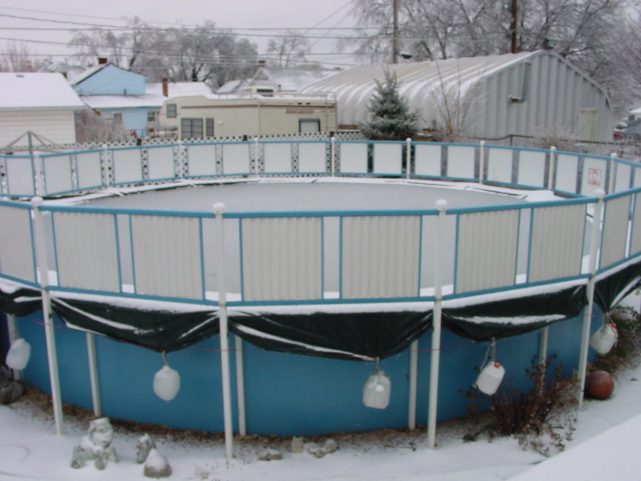 A snow-covered aboveground pool in a residential yard.
