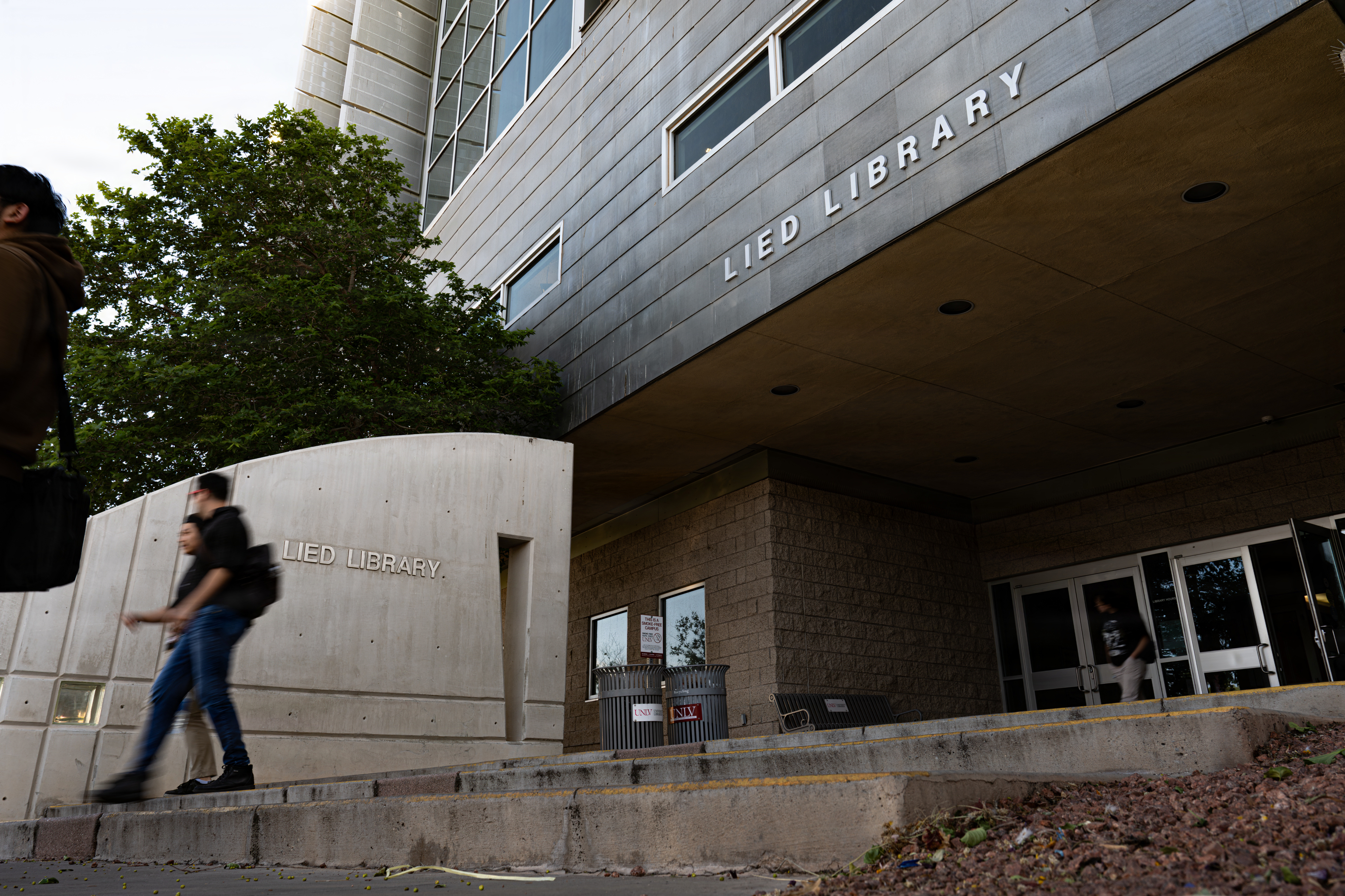 Students move down steps outside the glass-and-stone Lied Library entrance.