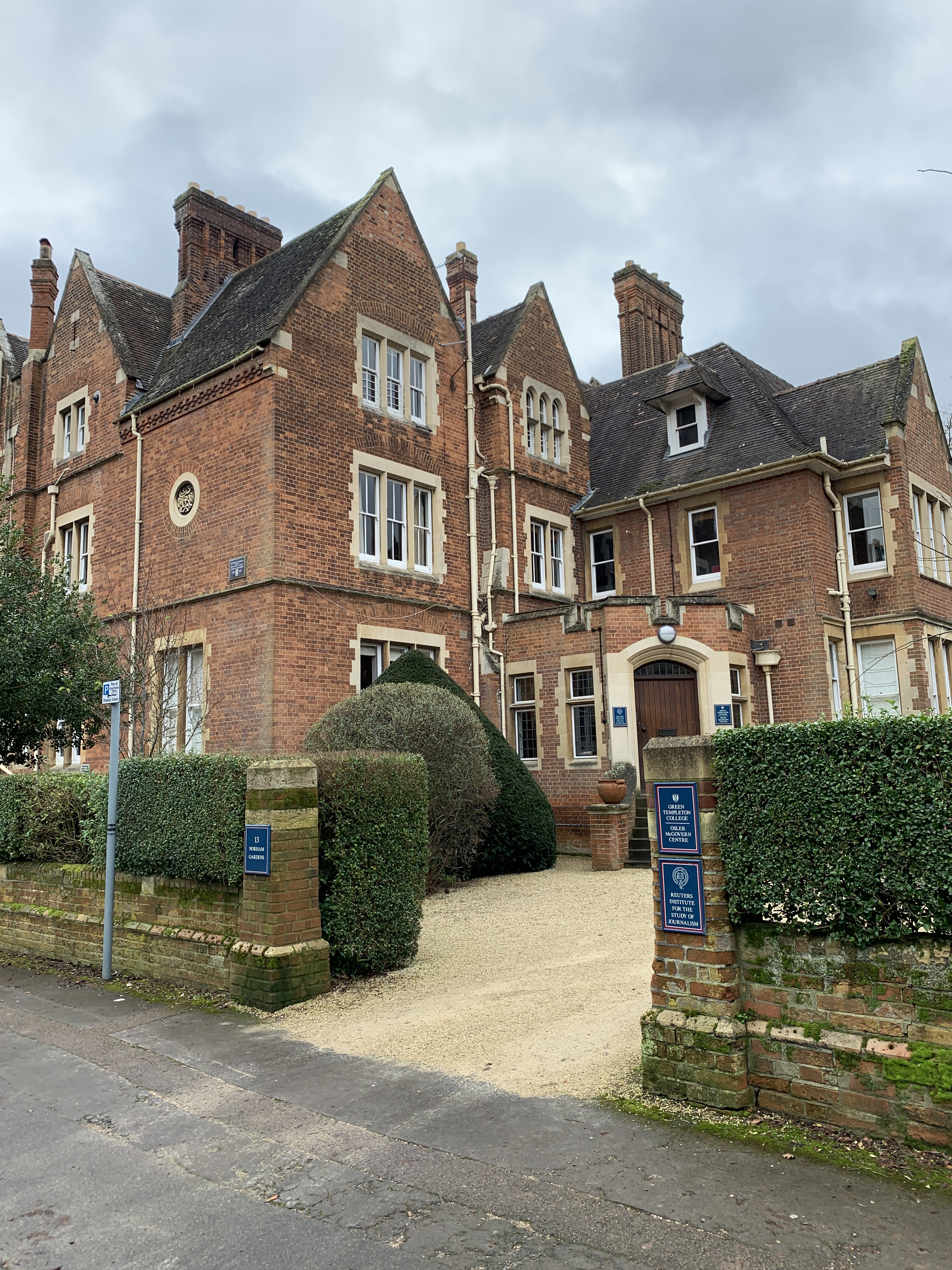 A brick building with a Reuters Institute sign beside its entrance.