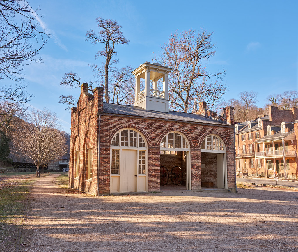 A brick engine house with arched doors and a white cupola.