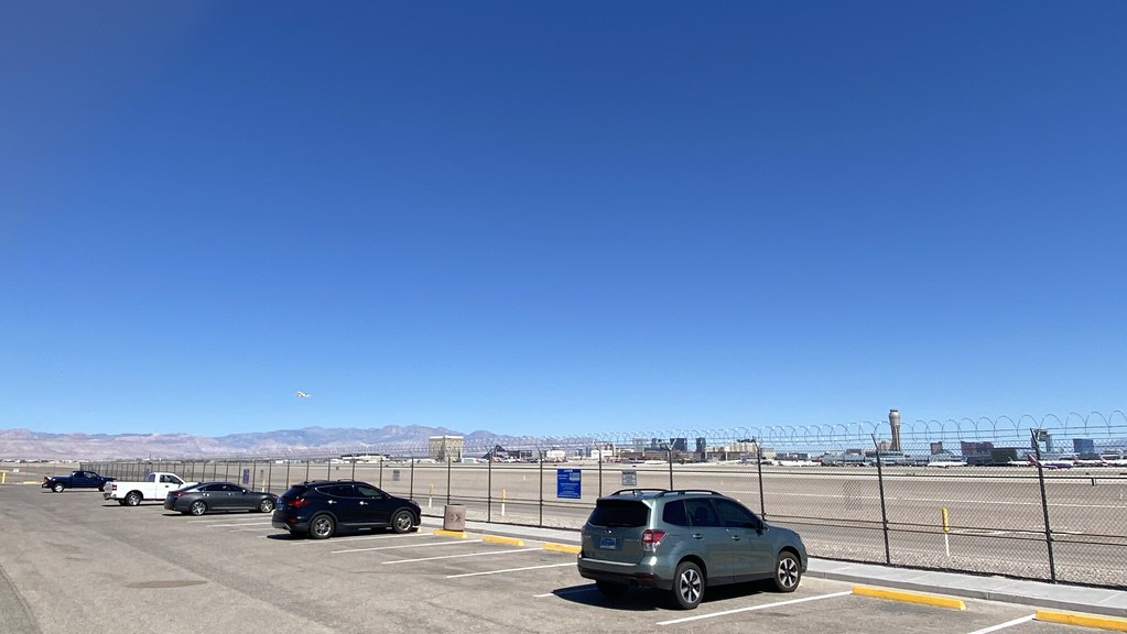 Runways beyond cars parked at the airport viewing area.