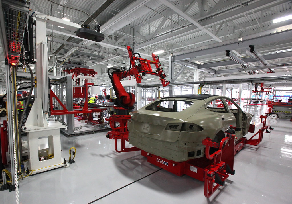 File photo (2011): a red industrial robot stands beside an unfinished car body in a factory.