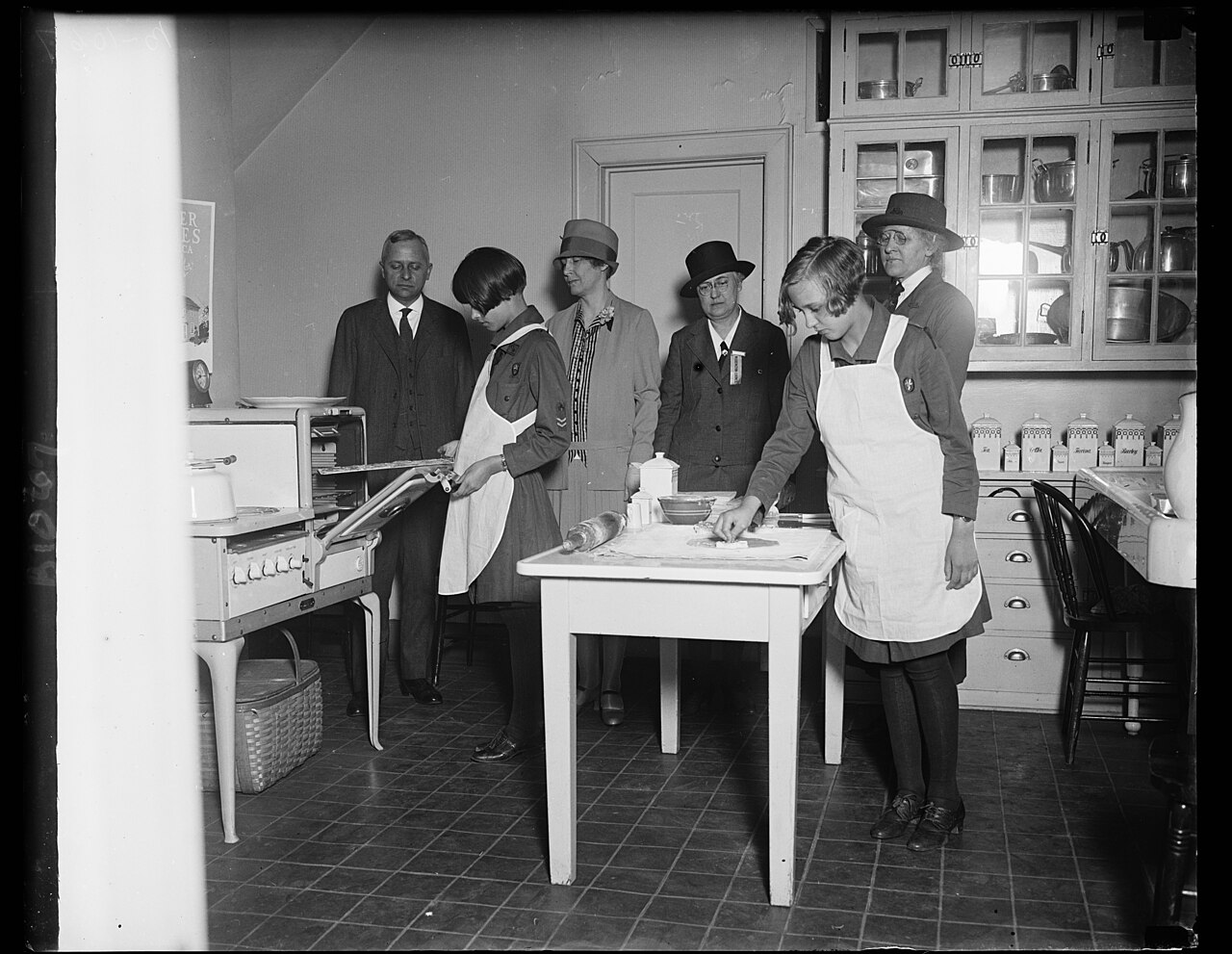 Girl Scouts baking with visitors in a kitchen.