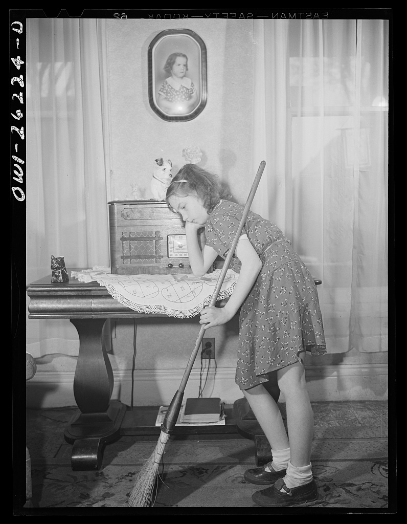 Girl with a broom beside a radio.