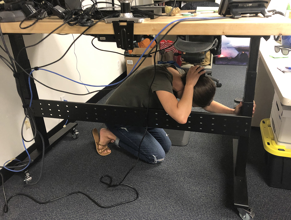 Staff member sheltering beneath a desk.