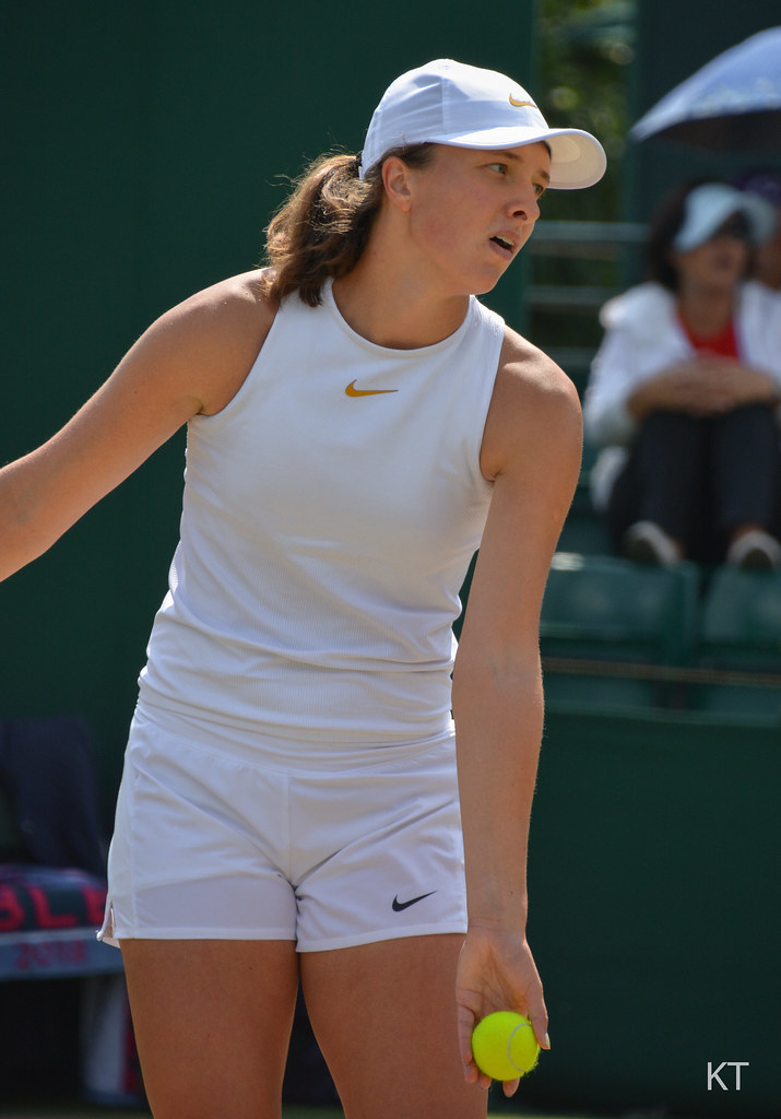 Iga Swiatek holds a tennis ball before serving.