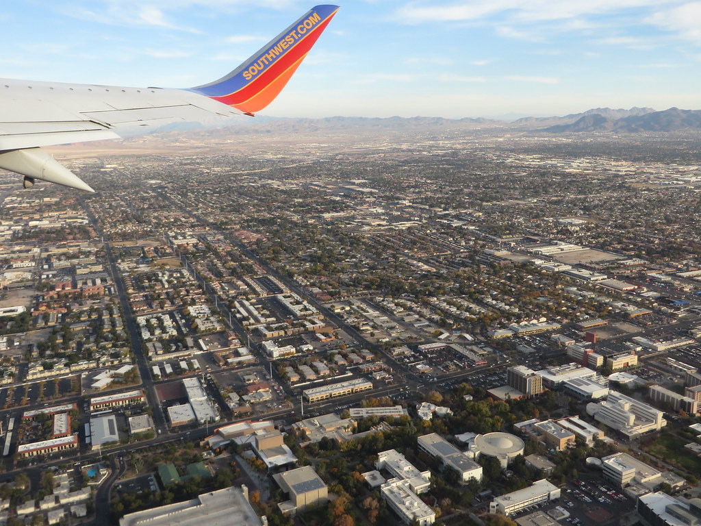 Airplane wing above UNLV campus buildings and surrounding Las Vegas Valley.