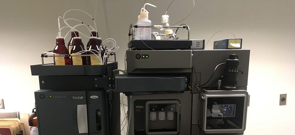 Liquid chromatography and mass spectrometry equipment with tubing and sample bottles.