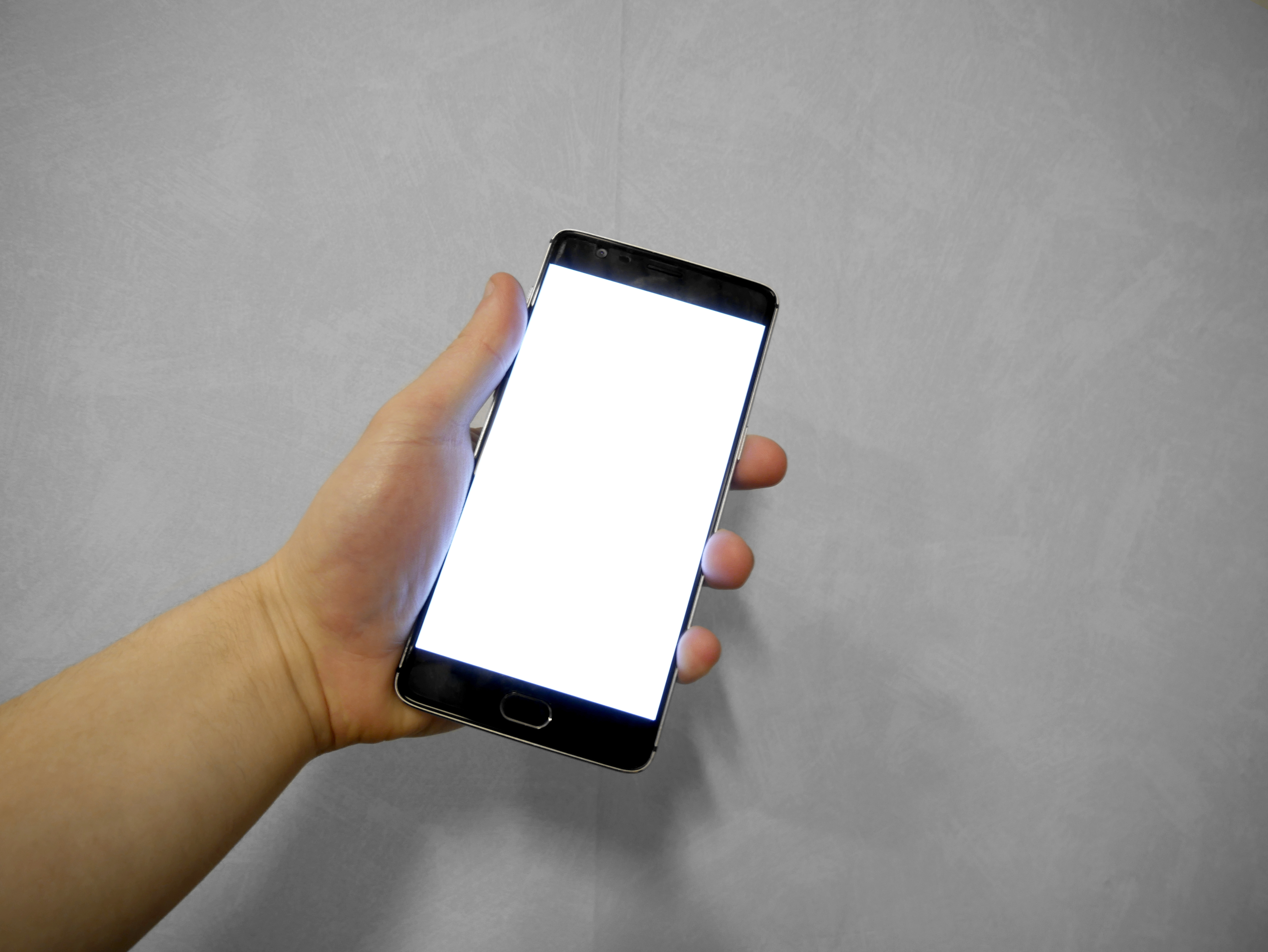 Hand holding a phone with a blank screen.