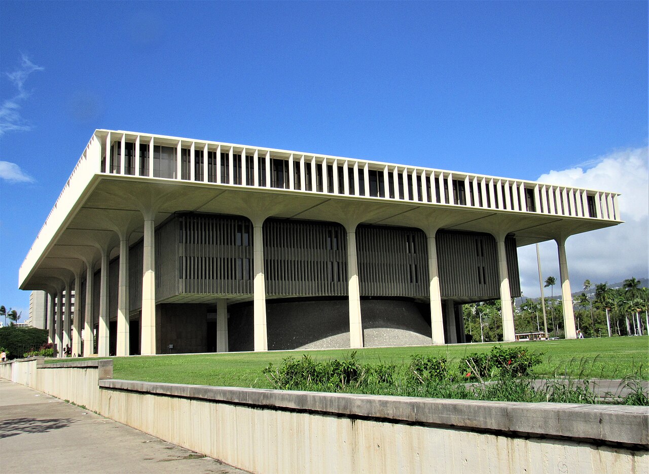 Open-sided capitol building with columns and lawn.