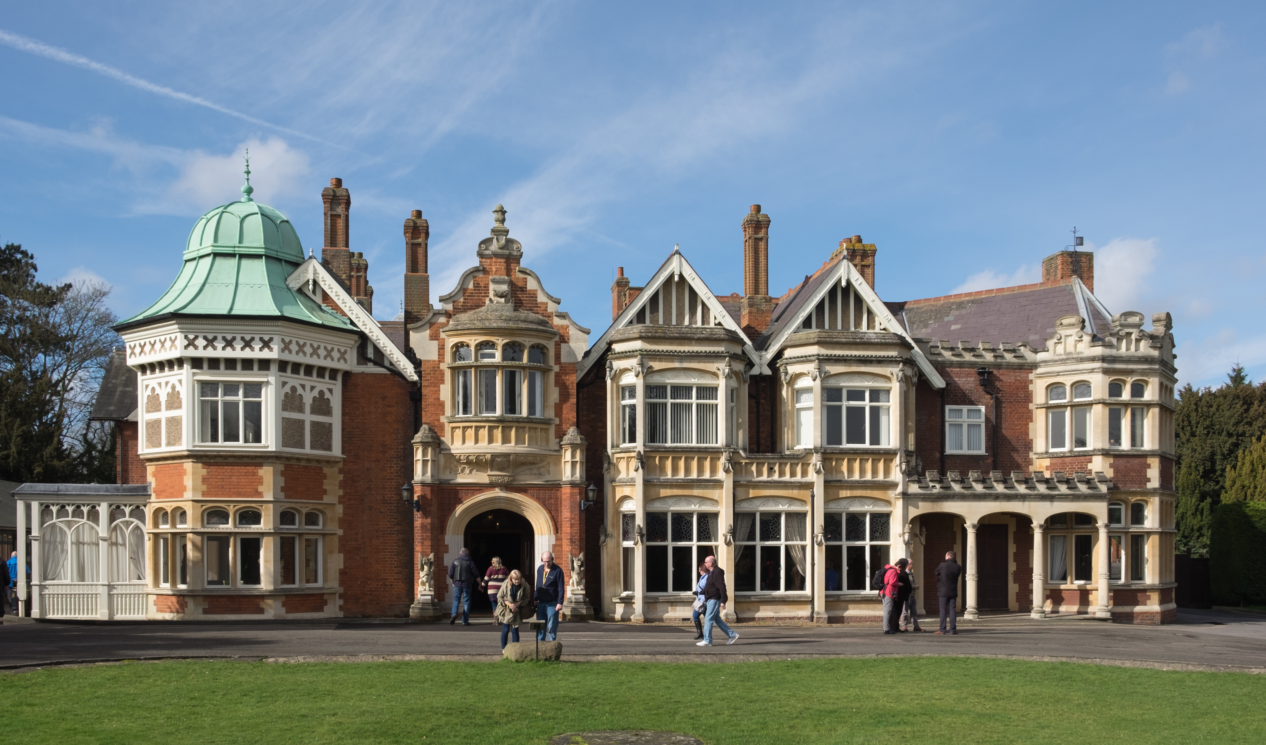 The brick and stone Bletchley Park mansion with visitors outside.