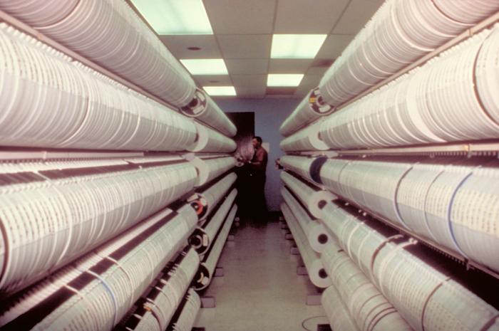 Rows of tape reels in a data-storage room with a person at the far end.