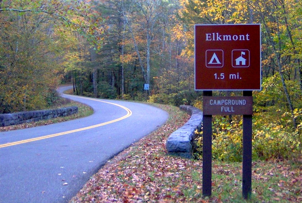 A wooded road and Elkmont sign with campground and lodging symbols.