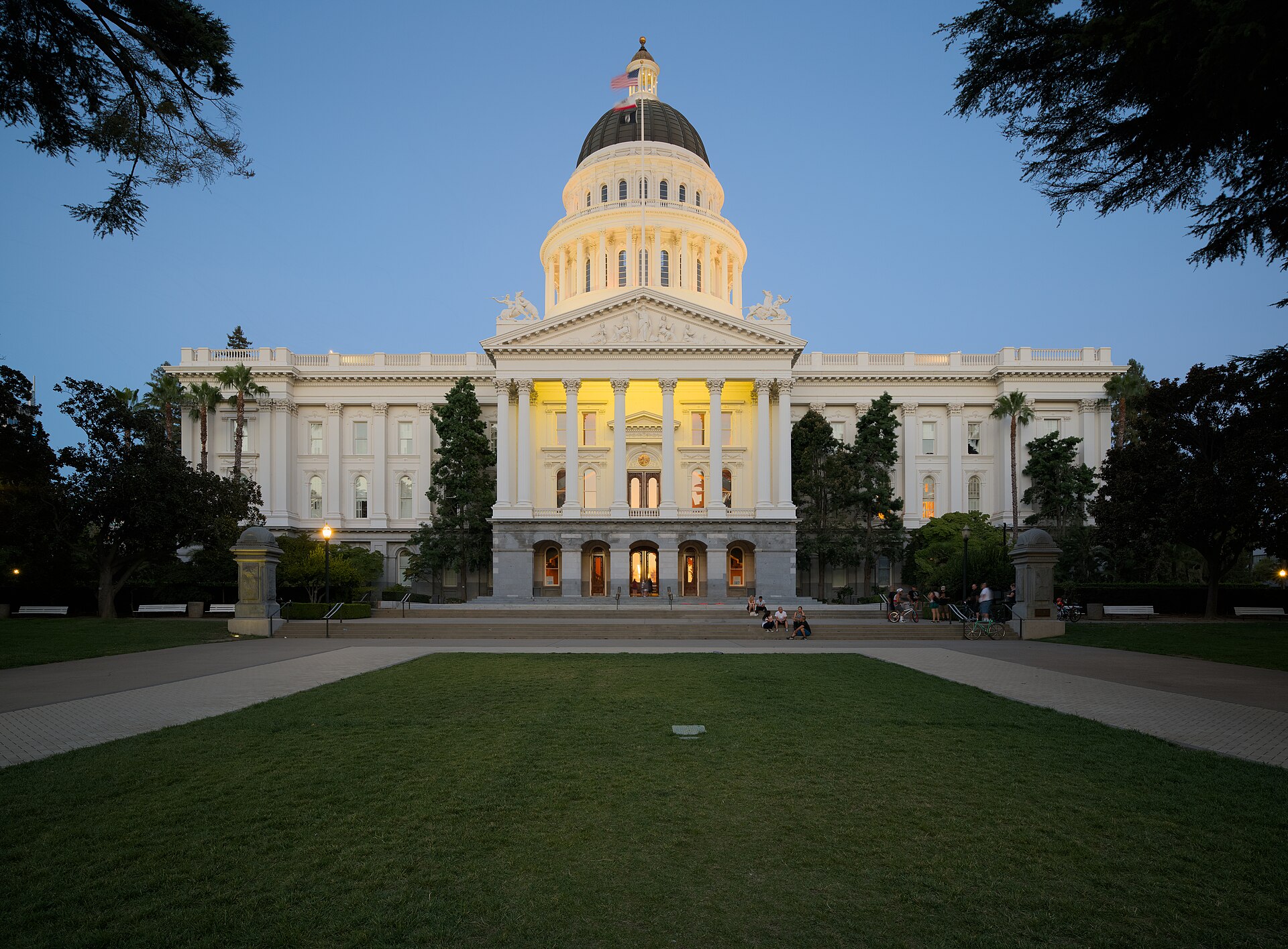 The California State Capitol illuminated against a blue evening sky.