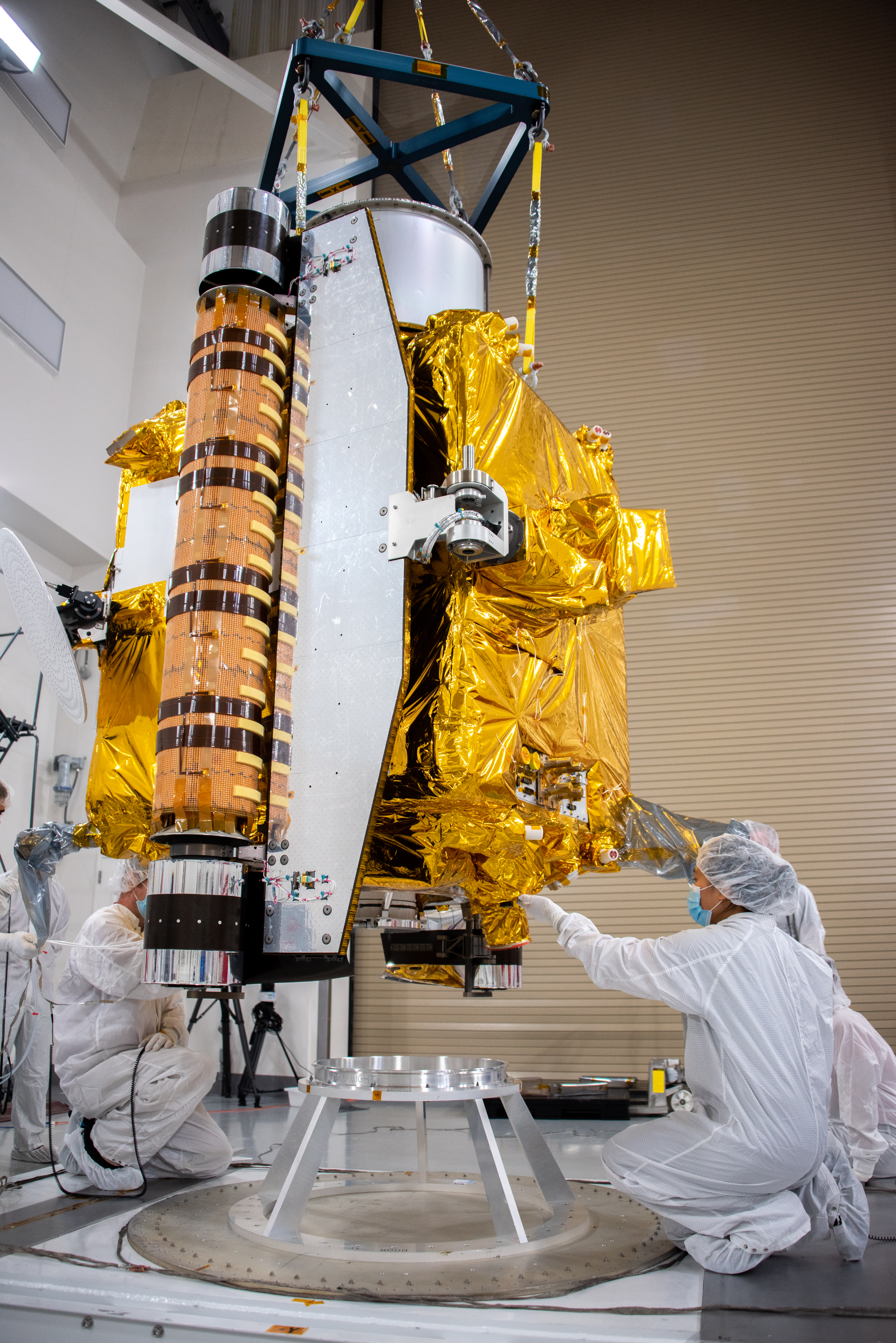 Technicians lower the DART spacecraft onto a stand.