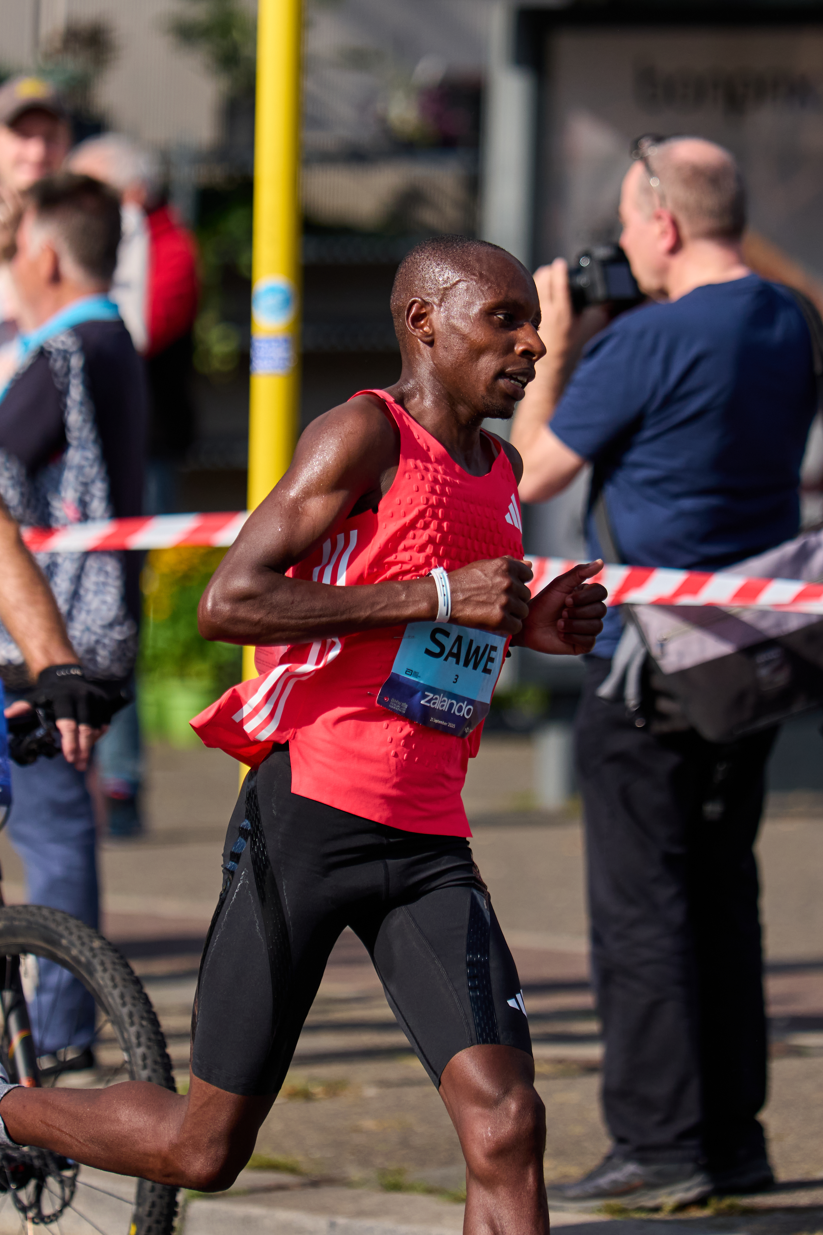 Sawe runs in a red vest with a SAWE race bib.