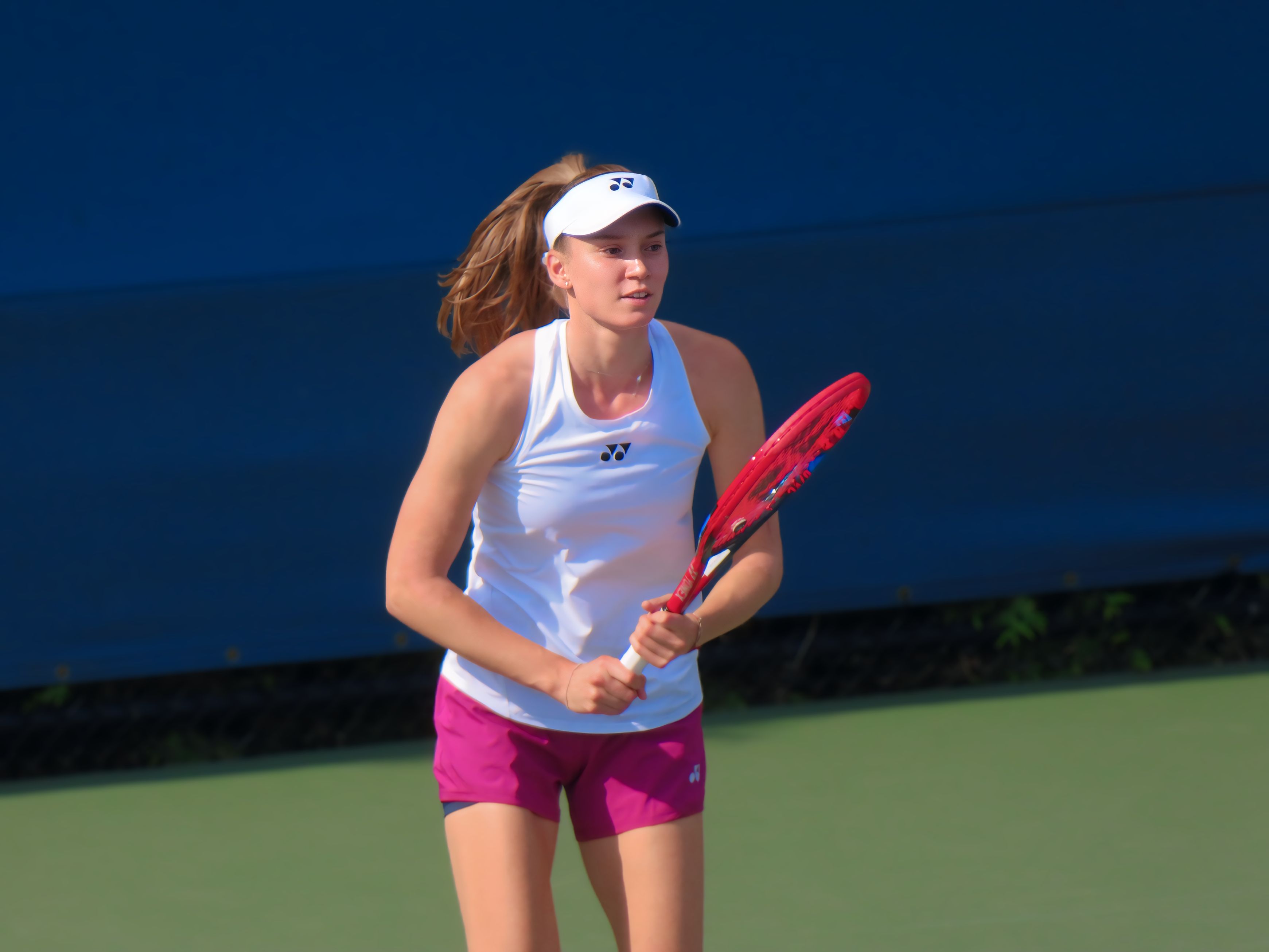 Rybakina holds a racket on a practice court.
