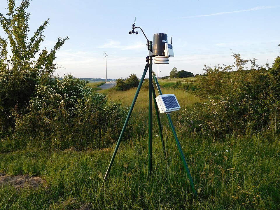 Weather sensors on a tripod in a field.