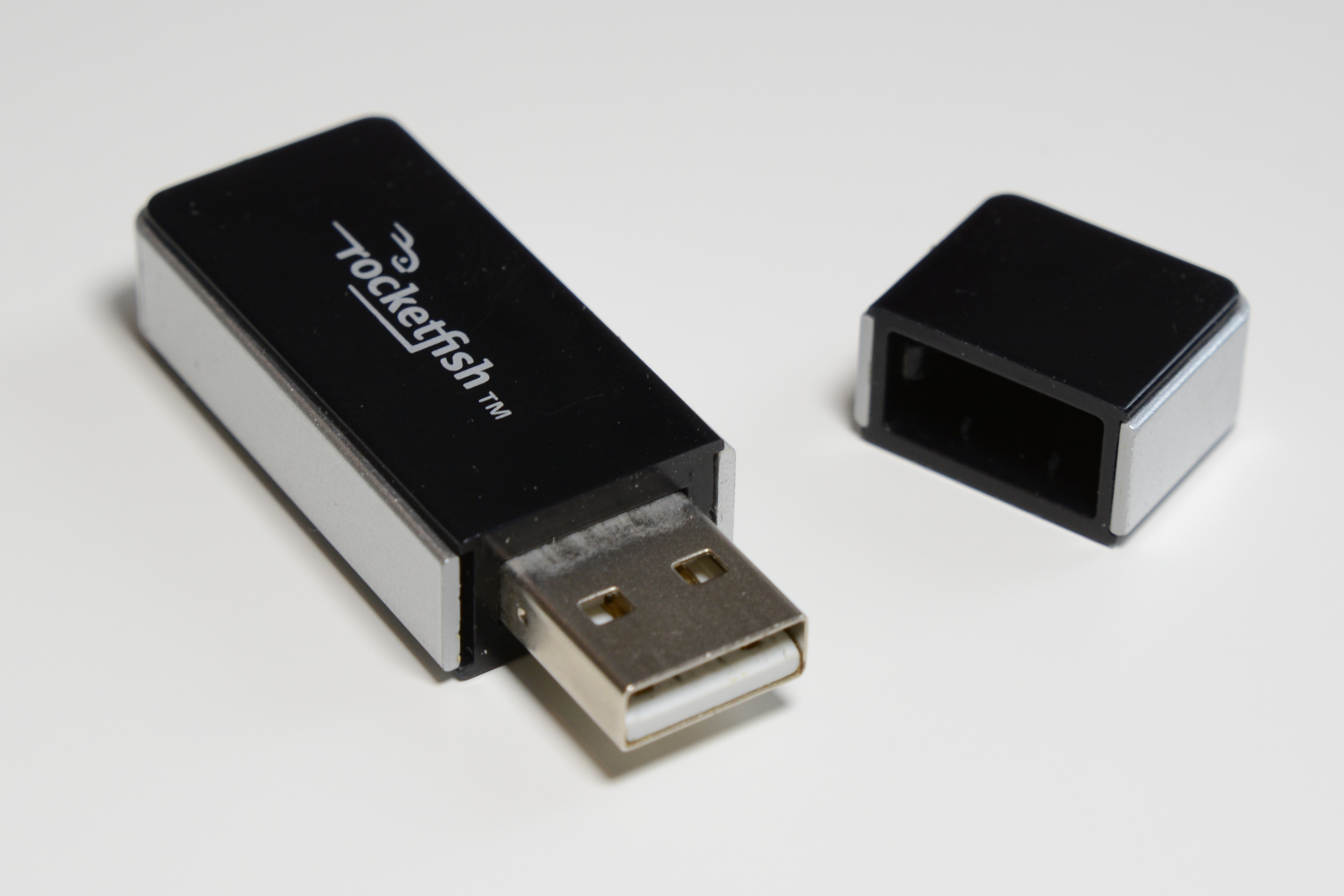 Black Rocketfish USB adapter beside its detached cap.