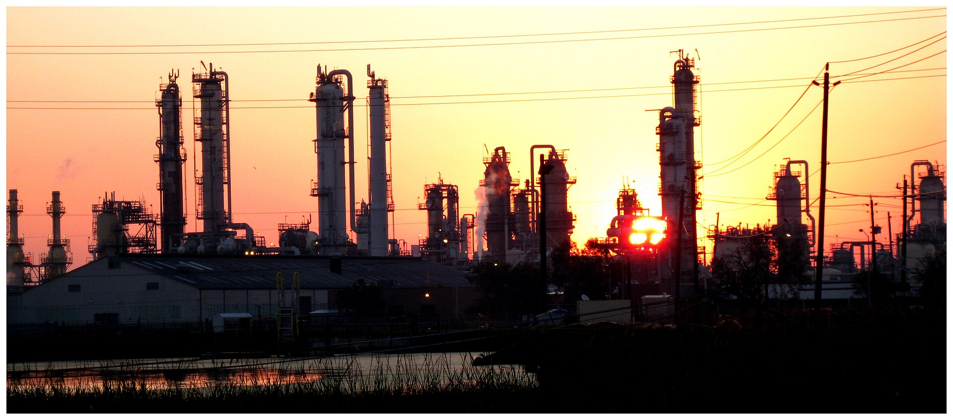 Industrial towers and piping silhouetted against a sunrise near Baytown, Texas.