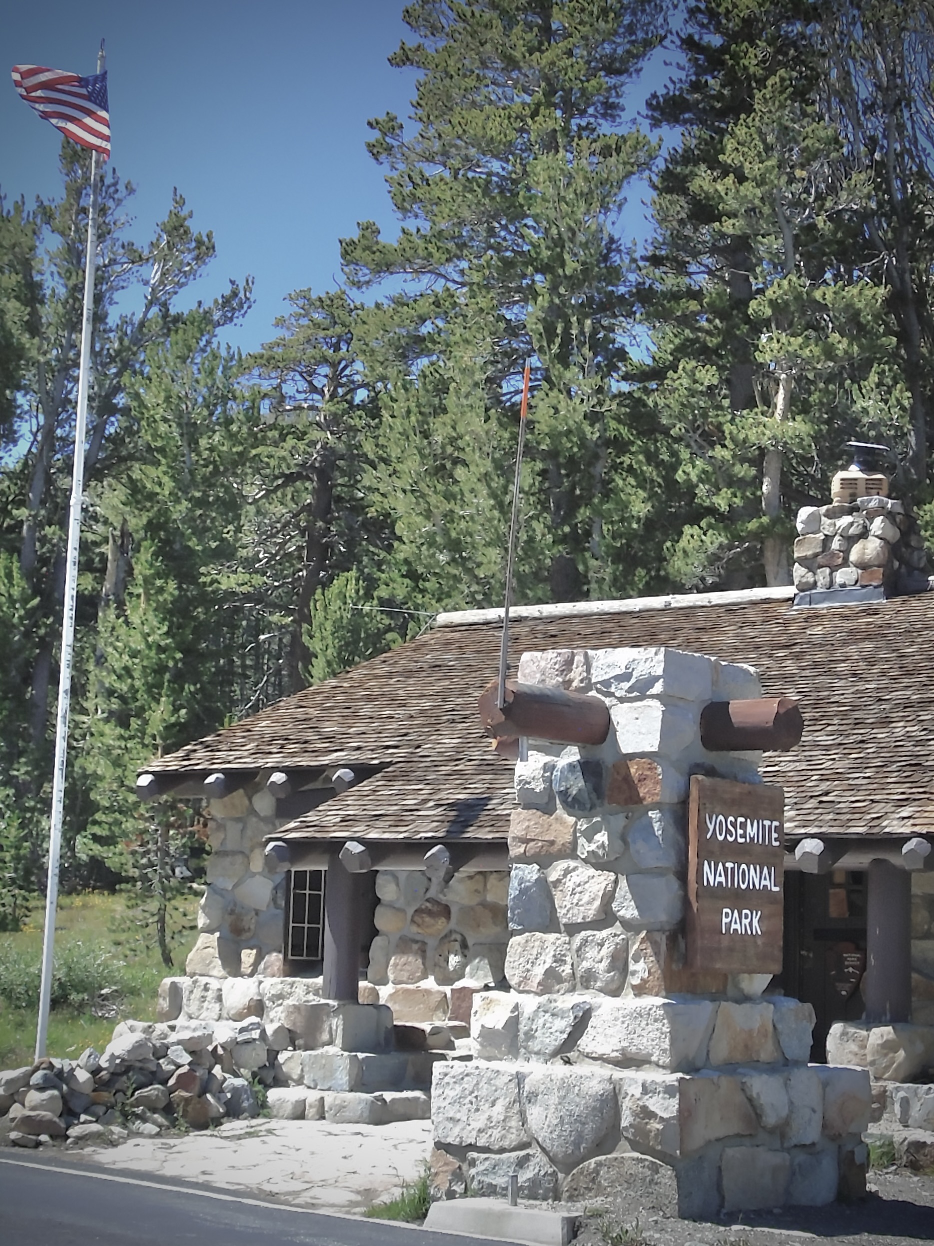 A Yosemite sign beside a stone entrance-station building.