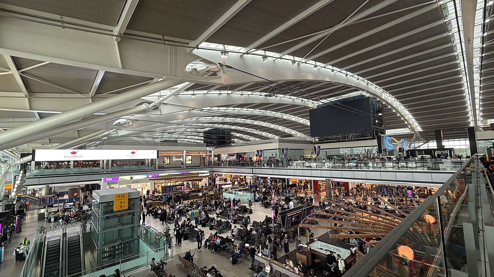 A wide interior view of Heathrow Terminal 5 with seating and shops.