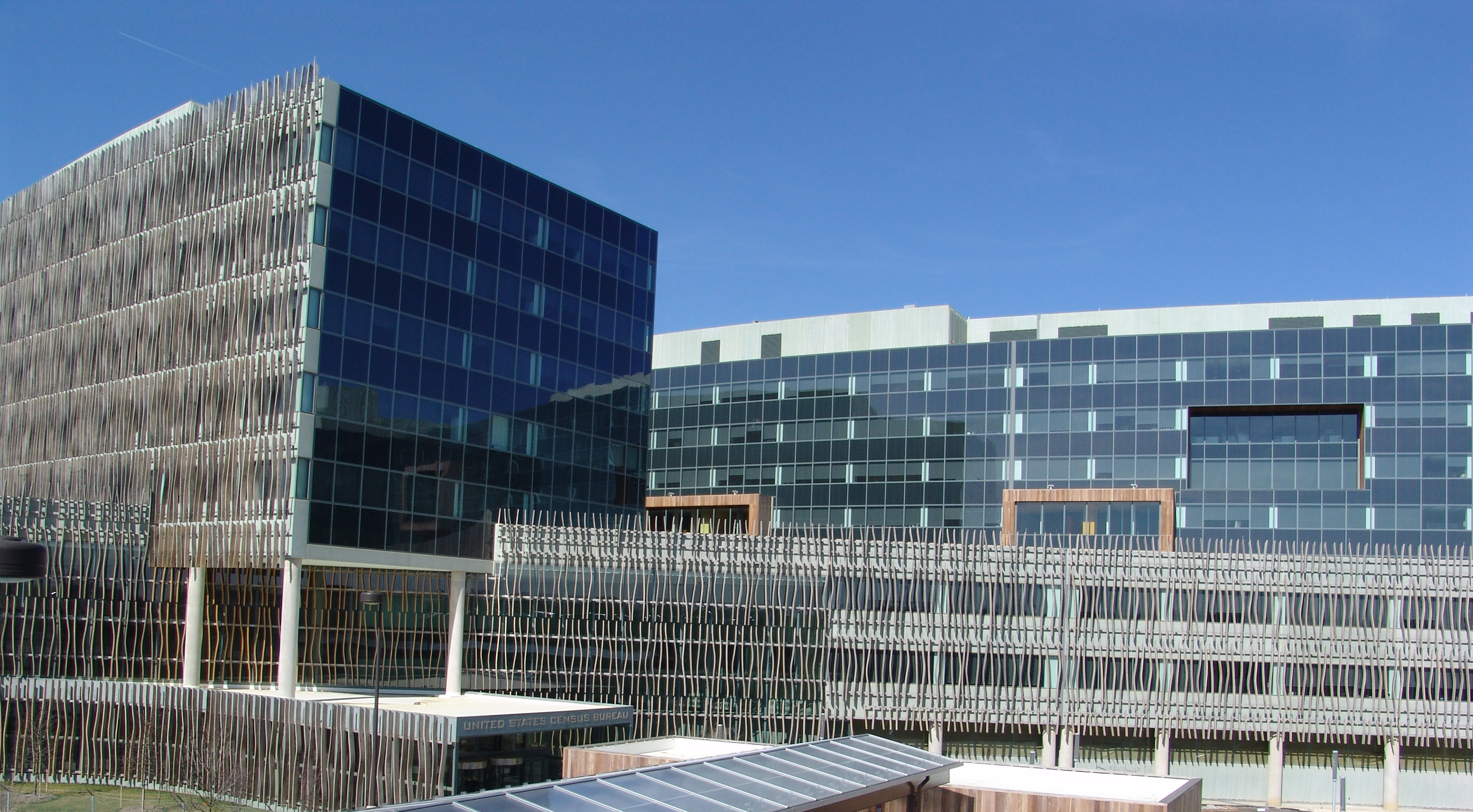 Glass-fronted Census Bureau headquarters buildings beneath a blue sky.