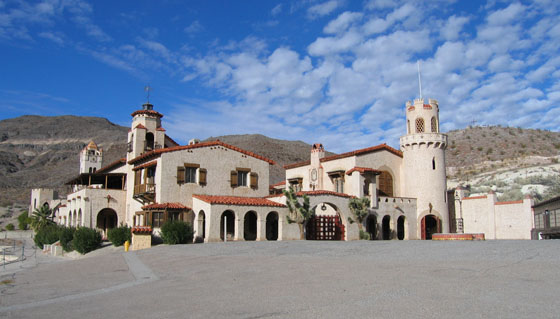 The pale Spanish Revival buildings of Scotty’s Castle beneath a blue sky in the desert.
