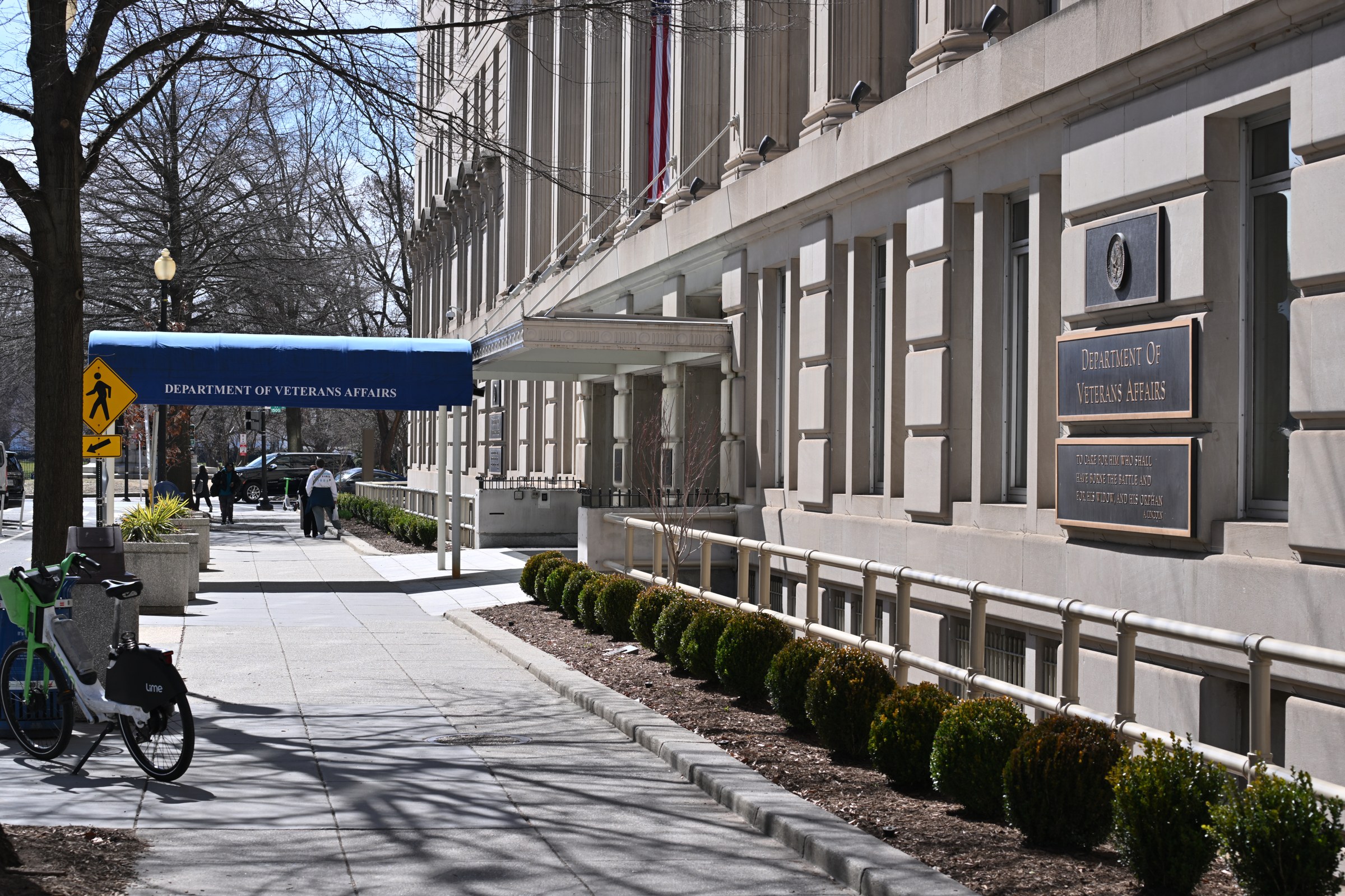 VA entrance awning and Department of Veterans Affairs sign beside a Washington, D.C., sidewalk.