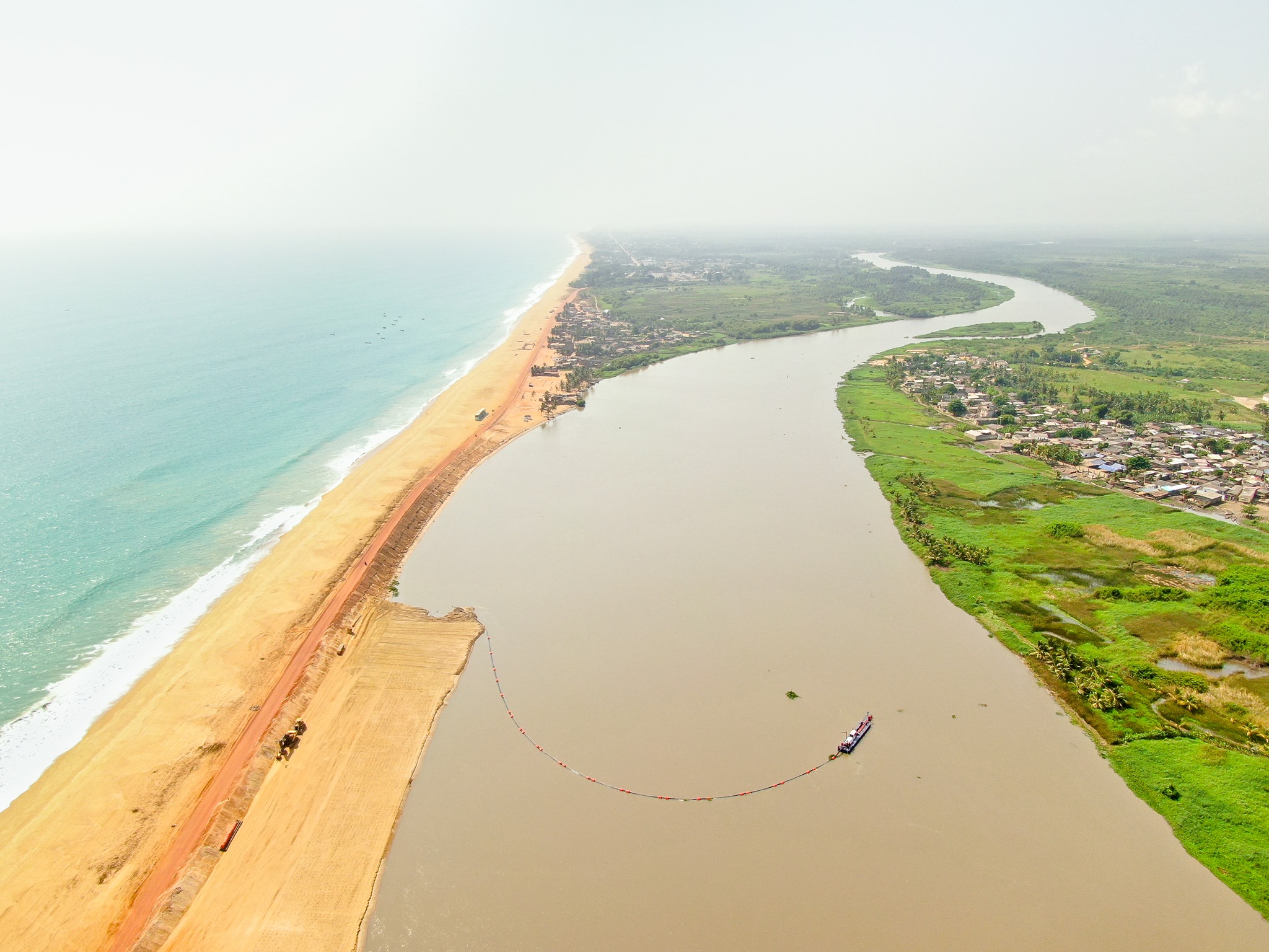 Aerial view of a broad lagoon beside a sandy coast and settlements.