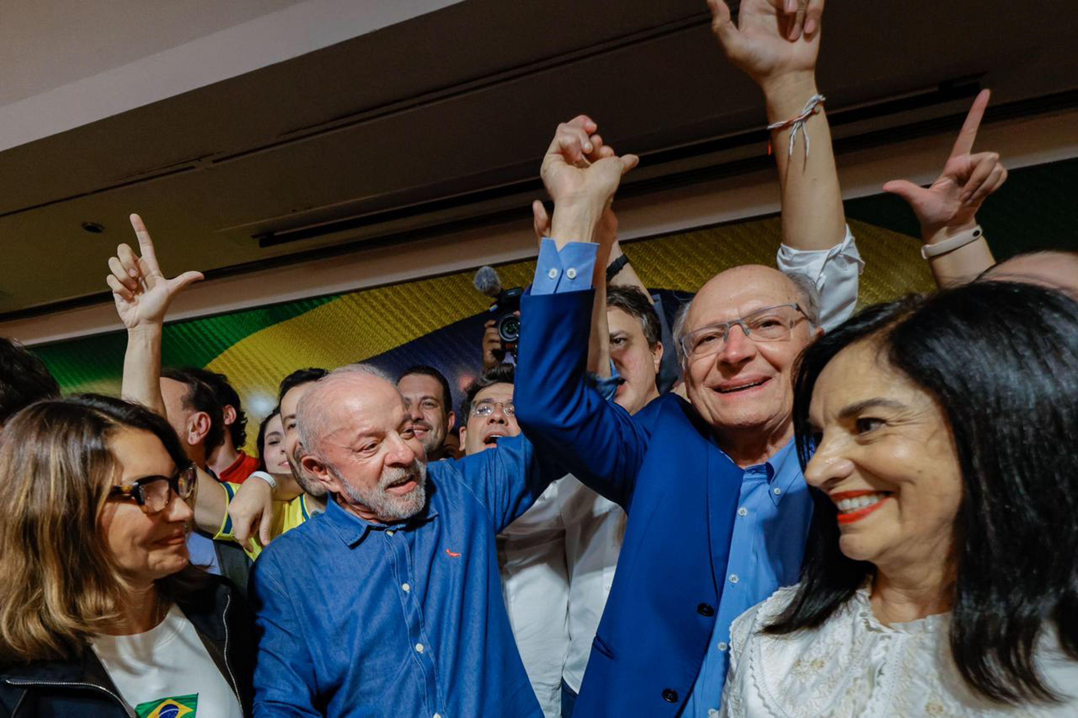 Luiz Inácio Lula da Silva raises an arm among people at a São Paulo reelection event.